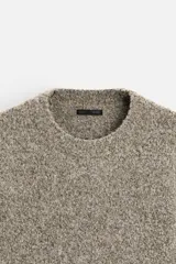 Sweater color arena con textura bouclé, cuello redondo, manga larga y terminaciones en rib.