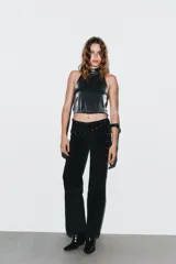 Top negro brillante con cuello halter ajustable con botones a presión, hombros descubiertos, detalle de tira elástica cruzada en la espalda y bajo abullonado.