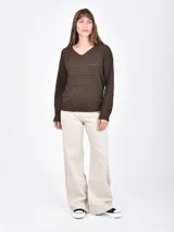 Buzo de tejido de punto negro, con cuello en V y mangas largas. Presenta franjas horizontales con pequeños calados decorativos.