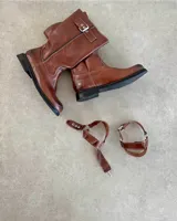 Bota de caña media de cuero negro con hebillas metálicas plateadas decorativas en la caña y alrededor del tobillo.