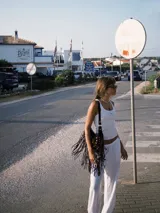 Bolso bandolera de cuero marrón con tachas y flecos.