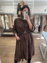 Vestido largo de pana fina color verde con estampado de flores marrones, corte oversize, mangas 3/4 y bolsillos laterales.