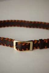 Cinturón de cuero color bordó con costura de tientos en color azul oscuro a lo largo de los bordes. Posee hebilla metálica rectangular plateada.