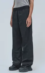 Pantalón negro de corte sastrero holgado, con dos bolsillos laterales, cintura elástica ajustable con tanca y cierre con botón y cremallera.