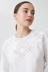 Blusa blanca con calados, cuello redondo, mangas largas abullonadas y corte peplum.