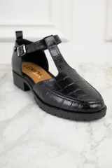 Zapato tipo mocasín negro con textura símil cocodrilo, tira central con hebilla y suela track.