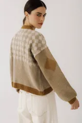 Cárdigan marrón con diseño de rombos en tonos rojizos y beige. Tiene cuello redondo, cierre frontal con botones y mangas largas con puños acanalados.