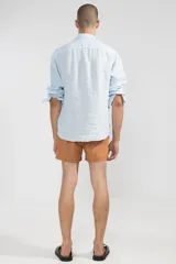 Camisa celeste de lino con botones de coco y corte recto.