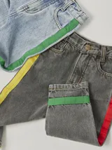 Pantalón de jean celeste con efecto lavado, corte recto y largo a la rodilla. Presenta una cinta vertical color violeta en la pierna izquierda, una cinta vertical color verde en la pierna derecha y una cinta horizontal color rosa en la parte inferior de ambas piernas.