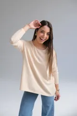 Sweater color beige de corte recto con cuello a la base. La parte delantera es más corta que la trasera y tiene una abertura en la parte baja de la espalda.