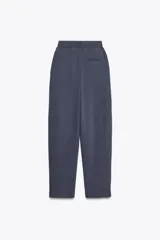 Pantalón color arena de tiro medio con cintura elástica, bolsillos laterales ocultos y pinzas en el delantero.