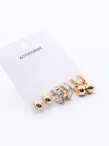 Set de tres pares de aros dorados. Un par de aros tipo argolla con forma de gota, un par de aros tipo argolla con incrustaciones de strass y un par de aros tipo argolla con dije de esfera colgante.