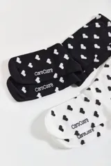 Pack de dos pares de medias de algodón, uno blanco con corazones negros y otro negro con corazones blancos.