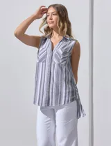 Blusa sin mangas con estampado a rayas verticales en tonos grises y blancos. Tiene cuello camisero, cierre frontal con botones y dos bolsillos con solapa en el pecho.