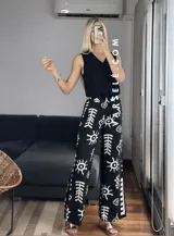 Pantalón palazzo blanco con estampado de motivos tribales en negro, cintura elástica y bolsillos laterales. Talle único.