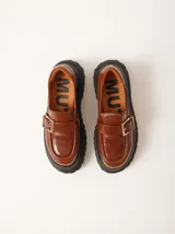 Mocasines marrones de cuero con hebilla dorada y plataforma track negra.