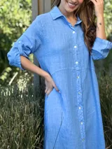 Vestido camisero largo de lino blanco, con corte en la cintura, abertura lateral y botones de nácar.