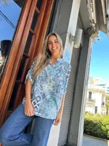 Blusa celeste con estampado floral en tonos azules, cuello mao con escote en V y cartera con botones de nácar.