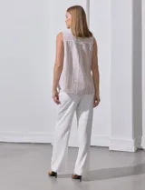 Camisa sin mangas de lino a rayas verticales azules y blancas, con cuello con solapa, escote en V, abertura central con botones y bolsillo en el pecho.