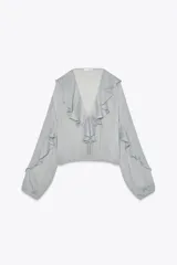 Blusa celeste de manga larga abullonada con puños elásticos, escote en V con volantes y lazos ajustables.