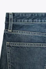 Pantalón de jean azul oscuro, de tiro bajo, corte wide leg y largo hasta el tobillo.