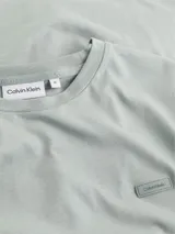 Remera de algodón gris claro, de corte clásico, cuello redondo y manga corta. Presenta un pequeño logo de Calvin Klein en el pecho.