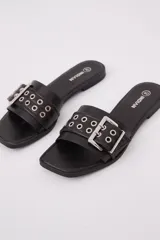 Sandalias destalonadas negras con hebilla plateada y detalle de ojales metálicos.