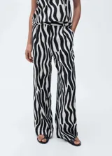 Pantalón largo de viscosa con estampado de cebra en blanco y negro, tiro medio, diseño recto y cierre frontal con botón, gancho y cremallera.
