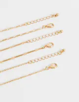 Set de tres pulseras doradas para mujer. Una pulsera es de cadena fina, otra con cuentas pequeñas y la tercera con dijes de mariposas.