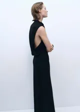 Vestido largo negro de tejido elástico con cuello drapeado y abertura lateral.