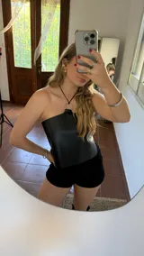 Top negro de ecocuero, sin mangas, con cuello halter y aro metálico.