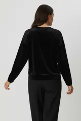 Buzo de terciopelo color marrón, de corte holgado, cuello redondo y manga larga.