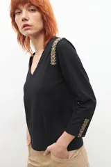 Remera fucsia con escote en V y detalles bordados en las mangas.