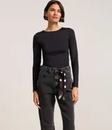Pantalón mom de jeans con lavado oscuro, con trabillas en la cintura y pañuelo estampado de lunares atado como cinturón.