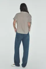 Camisa color gris claro con cuello solapa y escote pico, de manga corta. Presenta un nudo en la parte delantera y cierre frontal con botones.