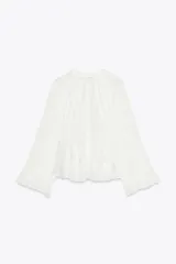 Camisa blanca de cuello redondo con escote en V y mangas largas acampanadas con volantes.