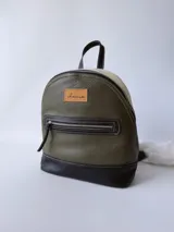 Mochila de cuero verde con detalles en blanco y negro.