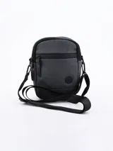 Bandolera negra con correa ajustable, cierre superior con cremallera y logo circular en el frente.