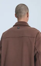Chaqueta marrón de paño con cuello clásico, cierre frontal con botones, dos bolsillos de parche en el pecho y corte holgado.