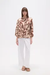 Camisa holgada con estampado de hojas en tonos marrones y beige, cuello mao, cierre frontal con botones y un bolsillo en el pecho.