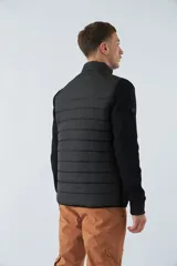 Campera negra con cuerpo acolchado de nylon y mangas de felpa. Tiene cuello alto, cierre frontal, bolsillos laterales con cierre, logo estampado en el pecho y logo de goma en la manga.