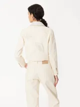 Chaqueta corta color crema de canvas con detalles en cuero genuino en cuello y cartera. Diseño con bordados de hongos y chiles intervenidos con strass.