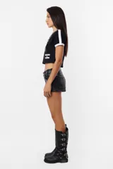 Remera corta negra de algodón tipo baby tee, con mangas cortas y detalles en blanco en cuello y mangas. Estampa frontal con la leyenda "Rocking Slaying" en blanco.