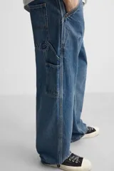 Pantalón de jean negro, corte relaxed fit, con bolsillos frontales y traseros tipo parche, tira multifunción y bolsillo tipo parche en las piernas. Tiene efecto lavado y cierre frontal con cremallera y botón.