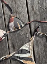 Conjunto de bikini azul con corpiño de triángulos movibles con almohadillas desmontables, que se ata al cuello y a la espalda. La bombacha es vedetina con tiritas a los costados para atar a medida de la cadera.