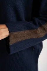 Sweater de punto azul marino con calce oversize. Presenta un detalle de franja vertical color marrón en la parte exterior de ambas mangas y un ribete fino dorado en el escote redondo.