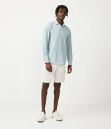 Camisa celeste de lino con cuello camisero, abotonadura frontal y mangas largas.