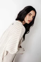 Poncho tejido de punto color crudo con lurex, de calce suelto y relajado.