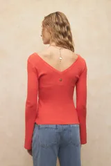 Top tejido color naranja, ceñido al cuerpo, con escote en V y mangas acampanadas.