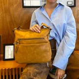 Bandolera marrón de cuero sintético con correa larga regulable combinada a tono. Tiene dos bolsillos frontales con cierre, apertura superior con cierre, división interna, bolsillos internos y bolsillo trasero con cierre.